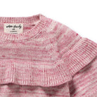 Close-up of a pink knitted garment with a brand label on a white background