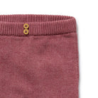 Close-up of a pink knitted garment with two buttons on a white background