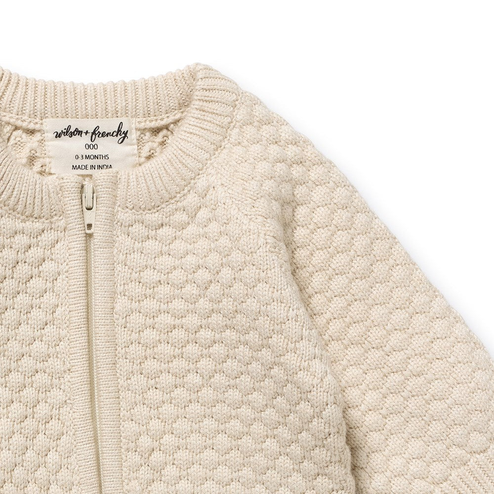 Beige textured baby jacket with a brand label on a white background