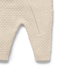 Close-up of beige textured baby romper on a white background