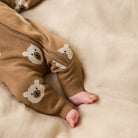 Brown baby romper with bear designs on a beige blanket