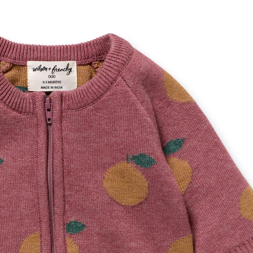 Pink baby onesie with orange and green pattern, brand label visible