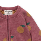 Pink baby onesie with orange and green pattern, brand label visible