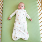 Baby lying in a crib with a floral-patterned white swaddle.