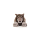 A plush stuffed animal of a brown and beige wolf or wild cat, lying down with its front paws extended, photographed against a seamless white background.