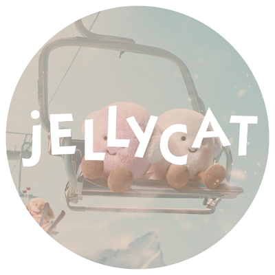 A pink and white Jellycat marshmallow on a ski lift with a background of blue sky and mountains