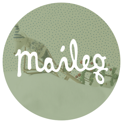 A Maileg mouse in a sweater and hat skiing on a bank of snow pulling a christmas tree behind them.