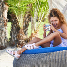 Young girl sitting on a lounge chair outdoors, holding a camera.