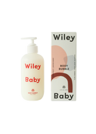 A bottle of Wiley Baby Body Bubble next to its product box on a plain white background. The bottle is frosted white with red text, and the box features a minimalist design with pink, brown, and gray abstract shapes and black text.