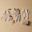 Collection of baby clothing and accessories on a beige background