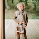 Child holding an abacus outdoors on a wooden deck