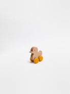 Wooden duck toy with wheels on a white background