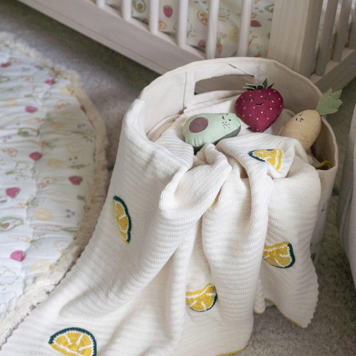 Baby blanket with fruit patterns on a crib in a nursery