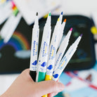 Hand holding a set of colorful markers with a blurred background