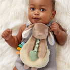 Baby holding a plush toy with colorful elements on a soft white background