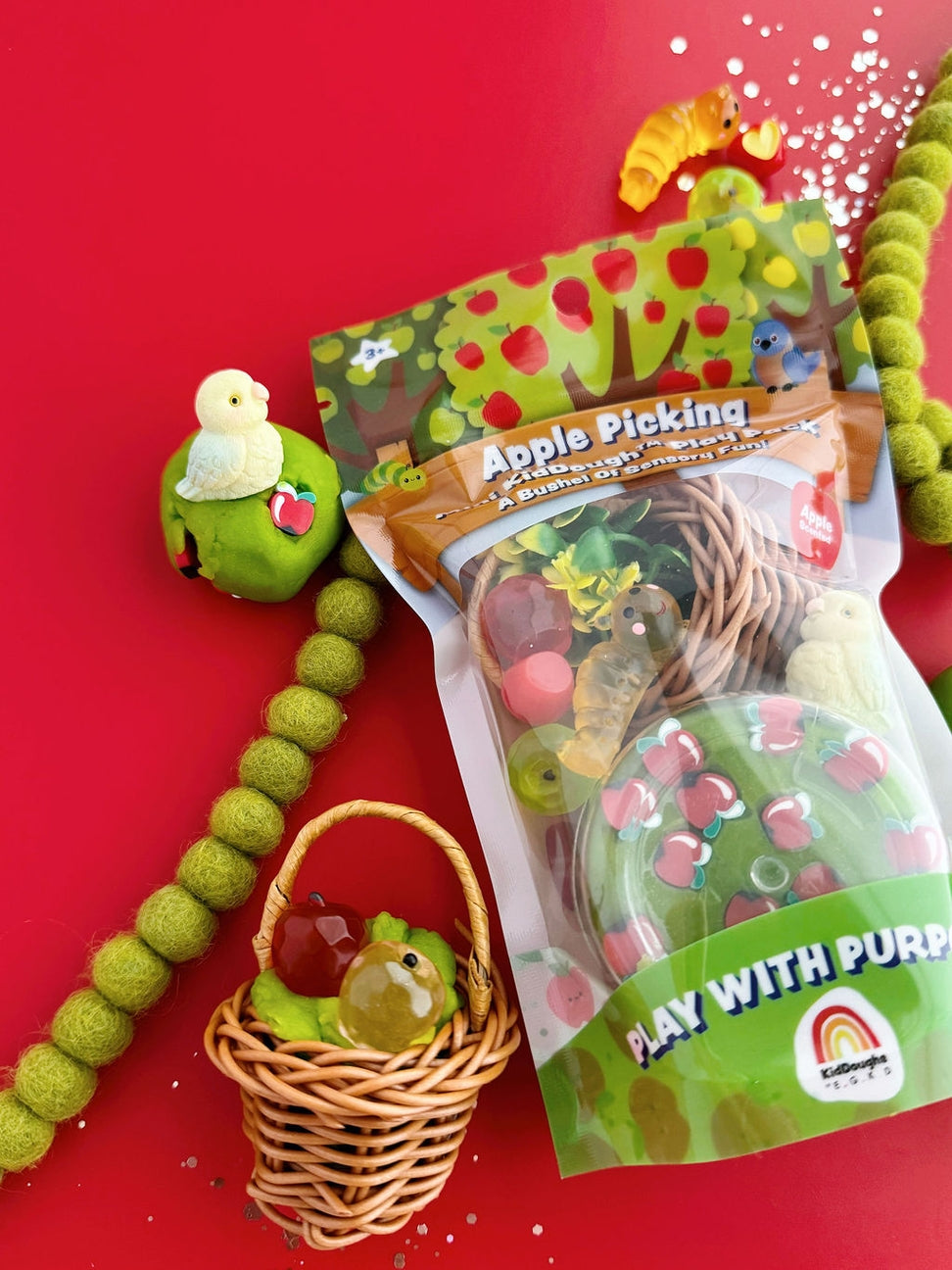 Toy set with apple-themed packaging on a red background