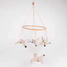 A fabric bird mobile hanging from a light wood ring on a white background. The mobile features four cream-colored birds with dark brown beaks and feet, suspended by thin cream cords from a wooden bead at the top.