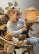 Child holding a teddy bear in a cozy room with soft lighting