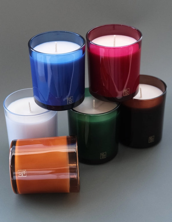 Set of colorful candles in glass containers on a gray background