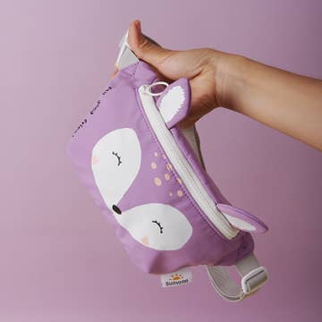 Purple fox-shaped pouch held by a hand against a pink background