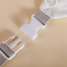 Close-up of a white plastic buckle with metal webbing on a beige background