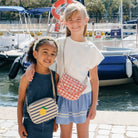 Two young girls standing by a marina with boats in the background