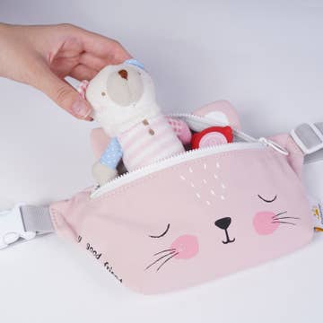 Pink pouch with cat face design and teddy bear inside, held by a hand on a light gray background