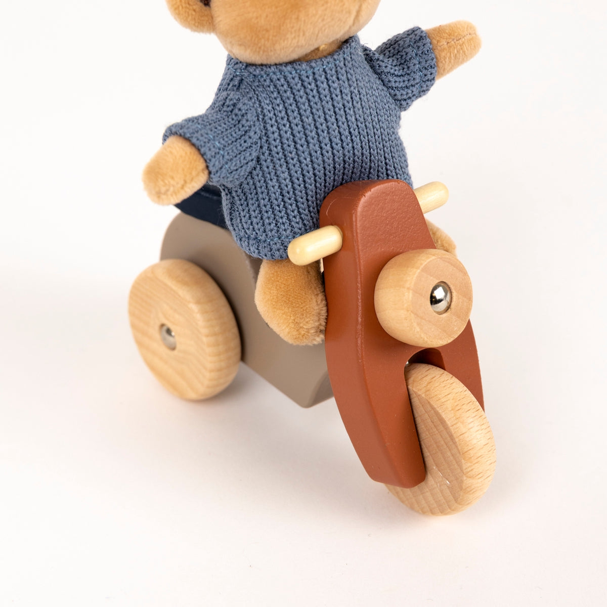 Wooden toy with a bear-like figure wearing a blue sweater on a white background