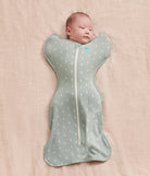 Baby wrapped in a gray swaddle with moon patterns on a pink blanket