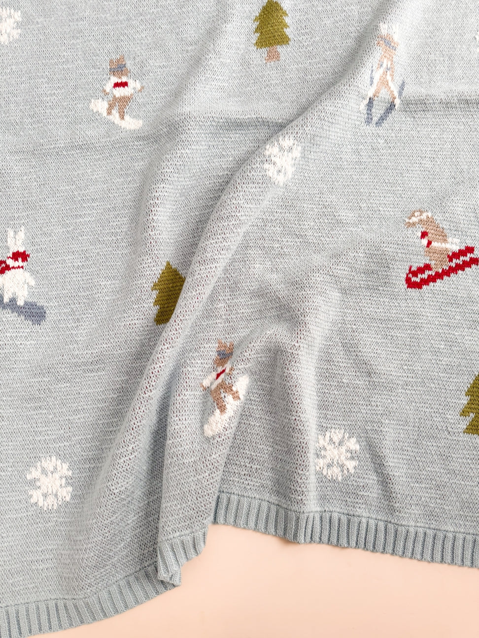 Gray sweater with Christmas-themed patterns including reindeer, trees, and snowflakes.