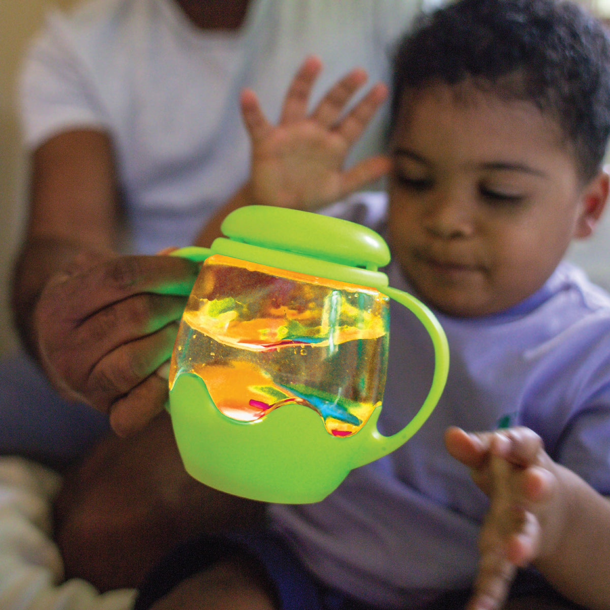 Child playing with a colorful toy cup featuring lights and fish.