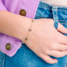 Close-up of a child's wrist wearing a gold bracelet with small beads, against a blurred background.