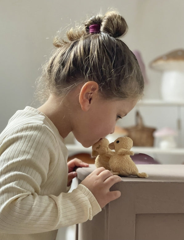 Child interacting with a teddy bear on a surface