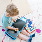Child sitting on a rug with a drawing board and coloring book