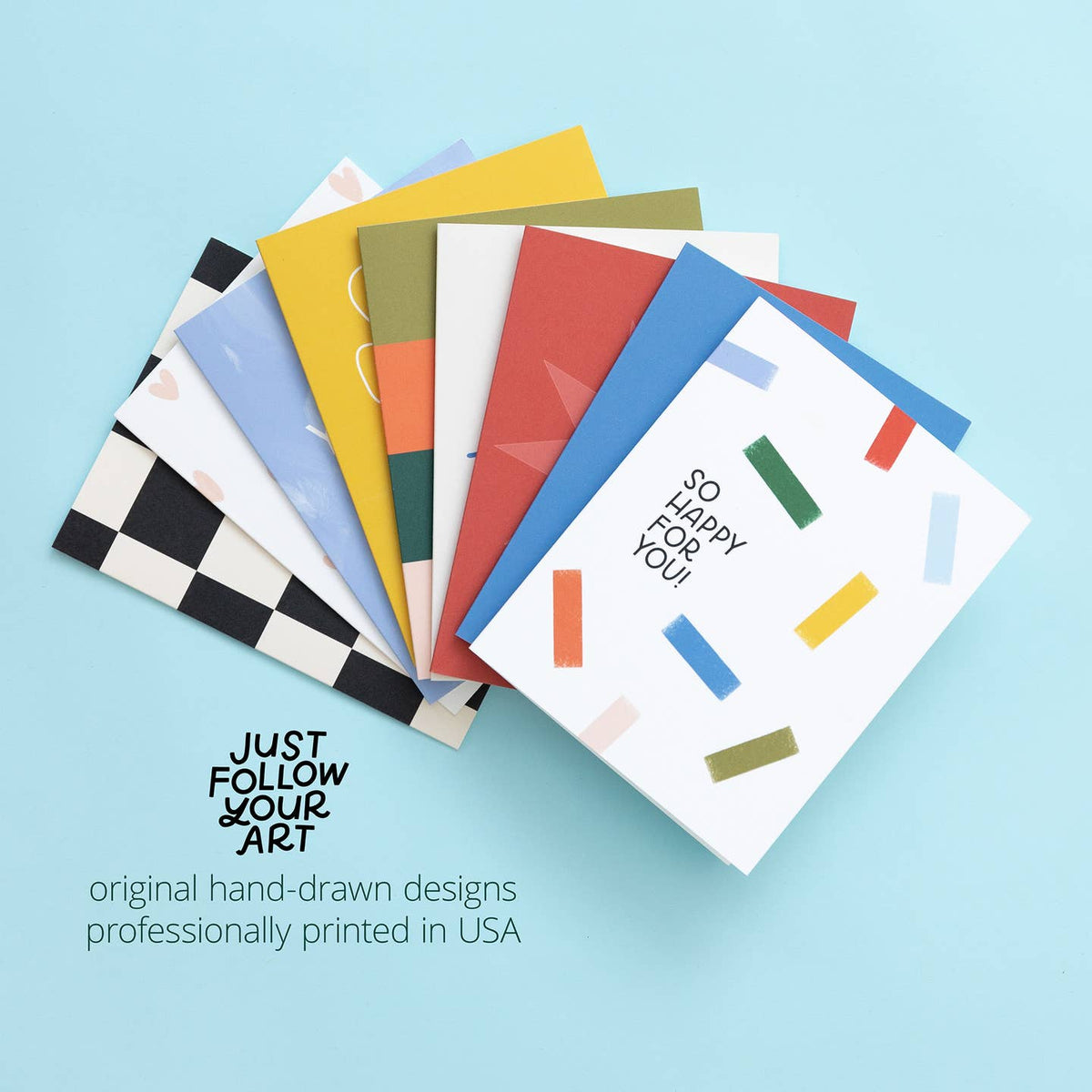 Stack of colorful greeting cards with geometric designs on a light blue background
