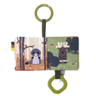A baby sensory fabric book with woodland animal illustrations, featuring a raccoon on birch trees and a moose in a forest, with olive green hanging rings and a small fabric tab.