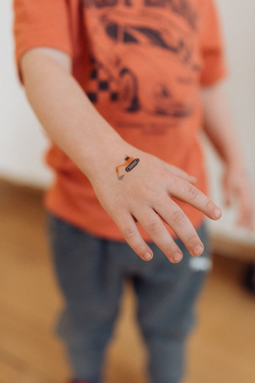 Child wearing an orange t-shirt with a graphic design, standing indoors.