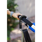 Hand holding a black stroller handle with 'The Mountain' branding, blurred background