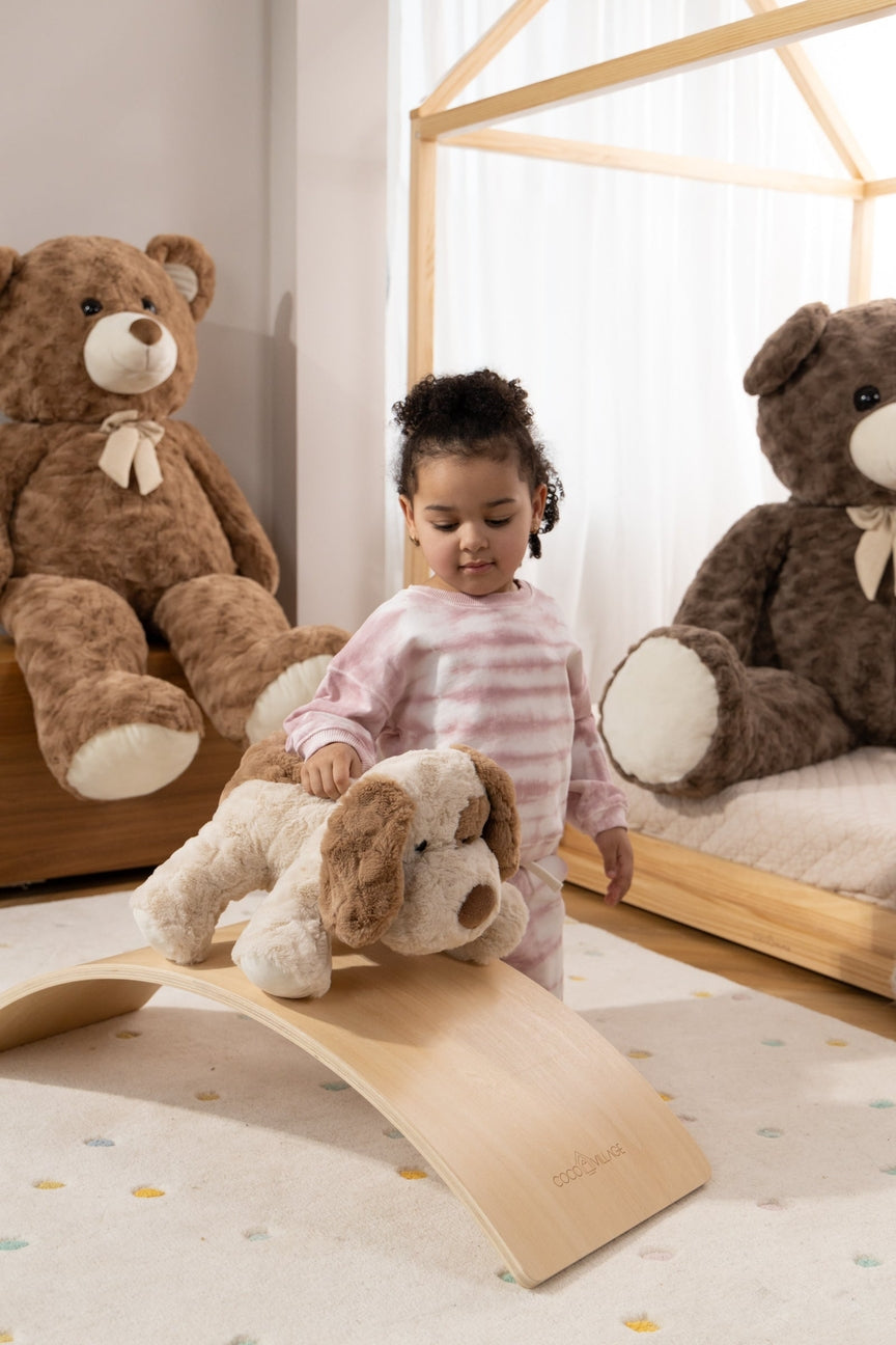 Child playing with a wooden balance toy in a room with teddy bears.