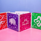 Set of colorful playing cards with animal illustrations on a pink surface and blue background