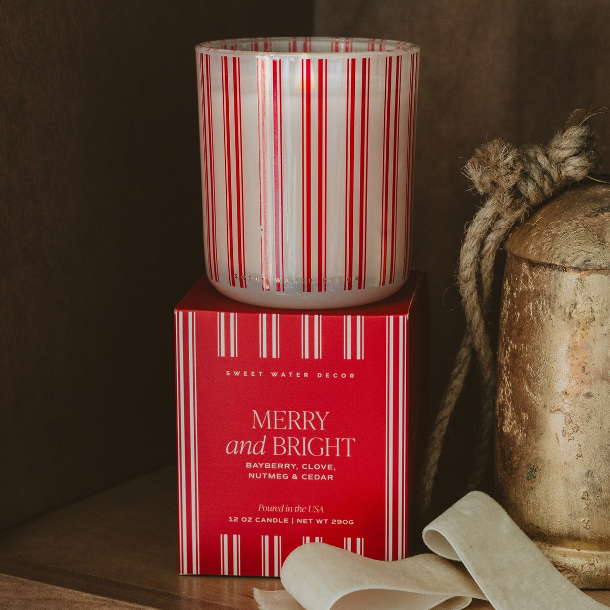 Decorative candle with red and white stripes on a matching box, surrounded by rustic elements.