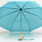 Blue umbrella with wooden handle on a light blue background