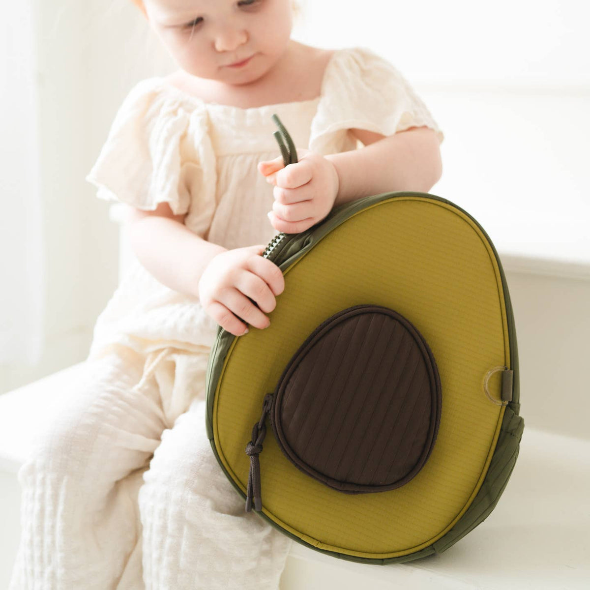 Child holding a green and brown bag on a white background