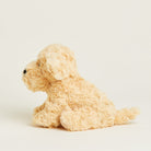 A side-profile view of the Golden Dog Junior plush toy by Warmies, showing its cream-colored textured fur and sitting posture.
