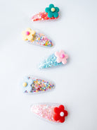 Set of colorful hair clips with flowers and sequins on a white background