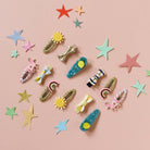 Colorful hair clips and star-shaped decorations on a pink background