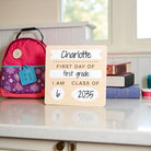 First day of school sign with backpack and books on a table