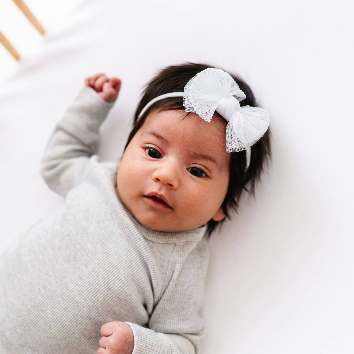 Baby wearing a white headband with a bow on a white background
