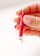 A hand holding a red and silver jewelry piercing tool with the brand name 'piercet' printed vertically on the handle, set against a clean white background.