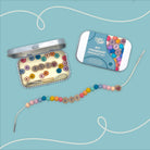 BFF friendship bracelet kit with colorful beads and a tin on a light blue background